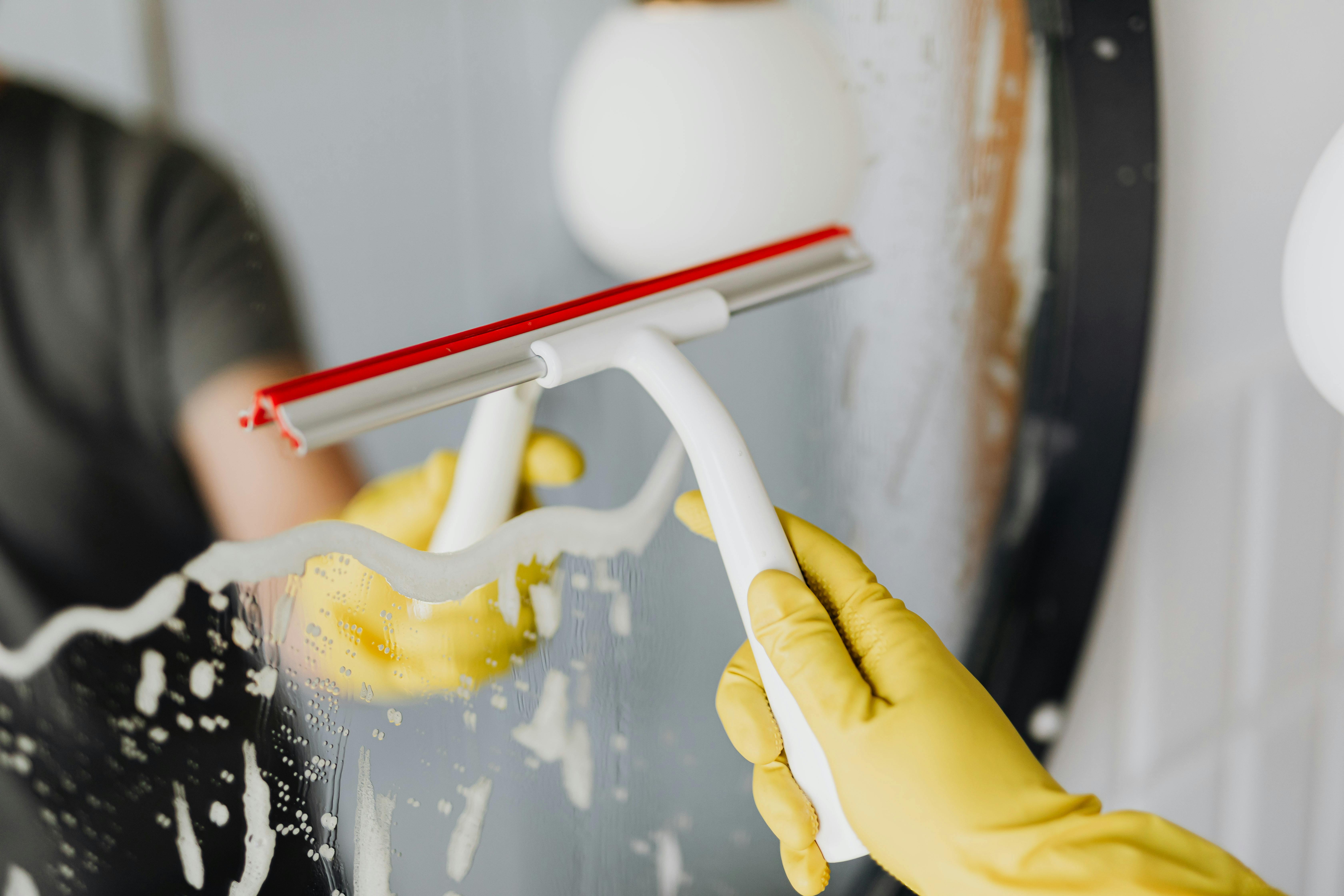 person cleaning mirror in bathroom