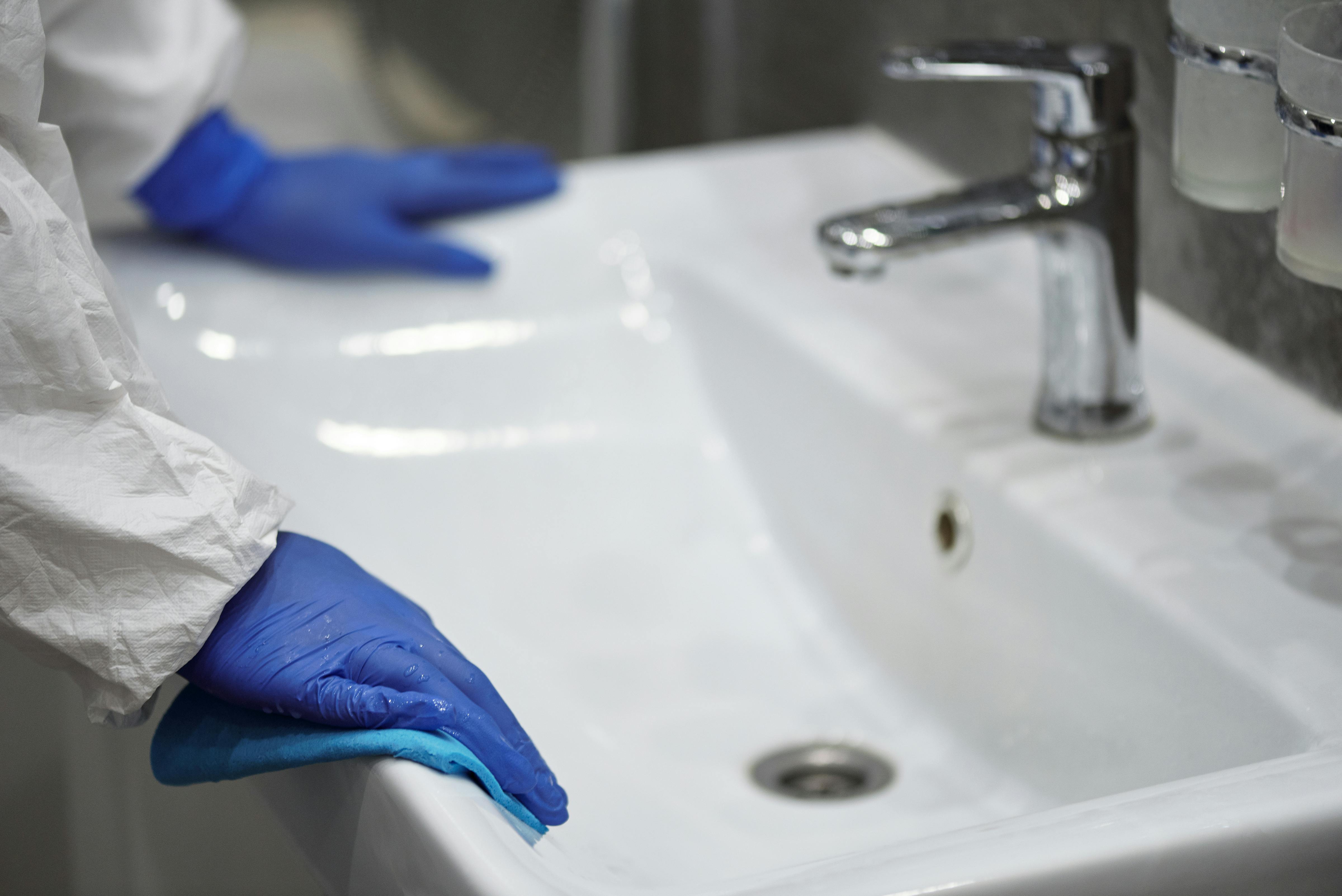 person cleaning sink in bathroom